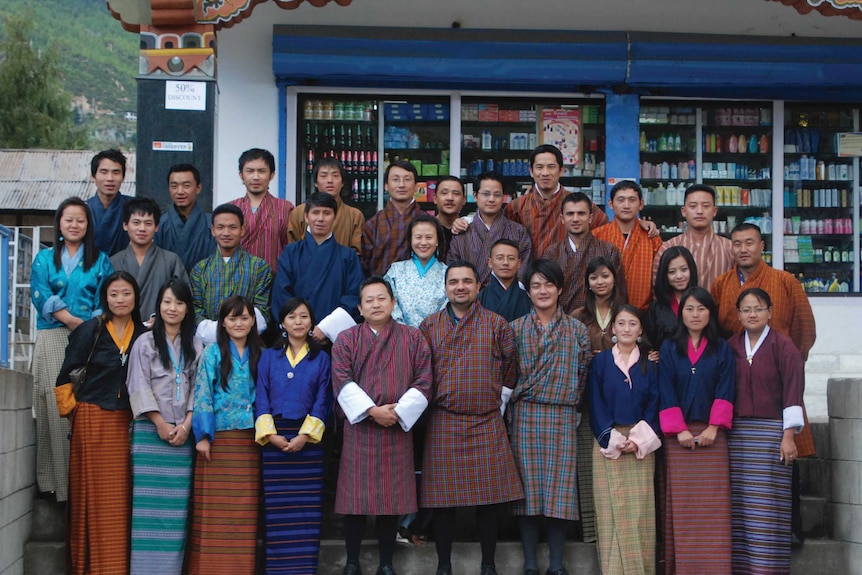 About 30 men and women wearing traditional Bhutan clothing.
