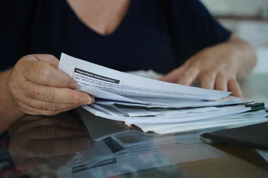 A woman's examines paperwork in her hands.
