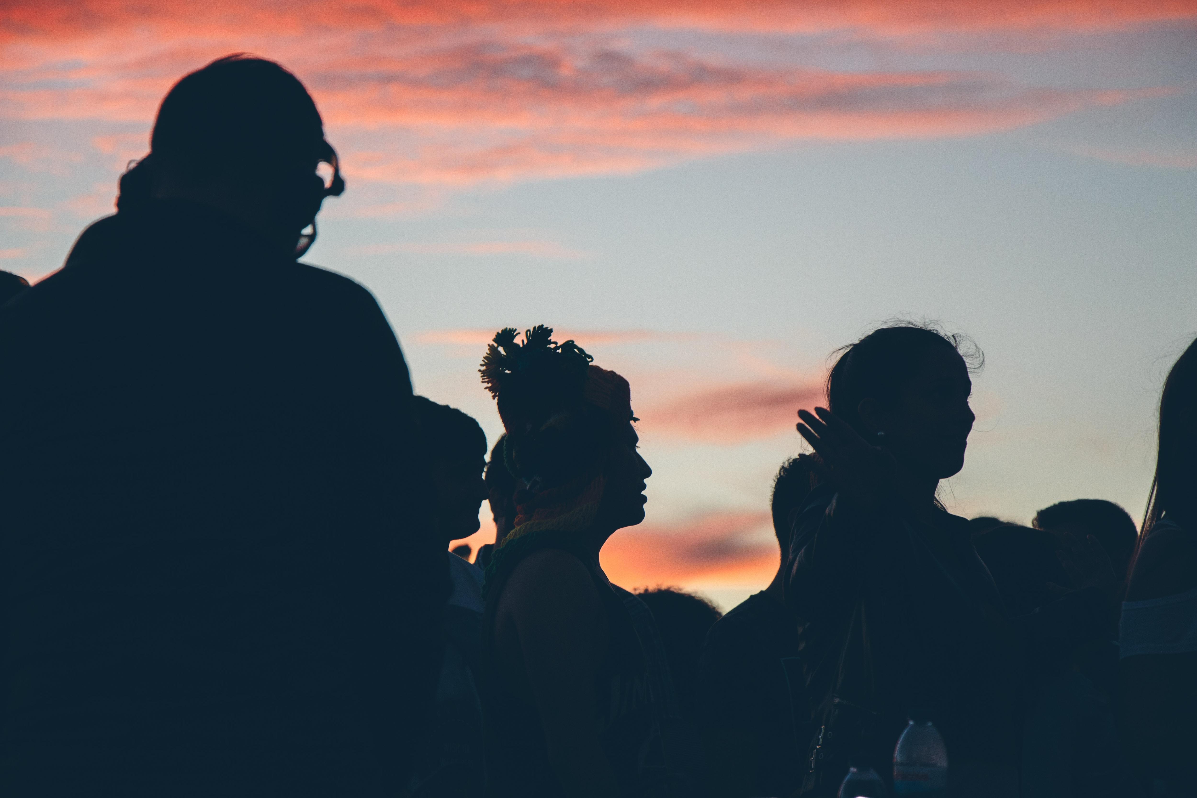 Under a pink night sky, there are silhouetted images of a group of young people standing.