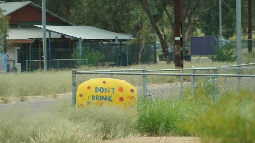 A sign saying "don't drink" stuck to a fence.