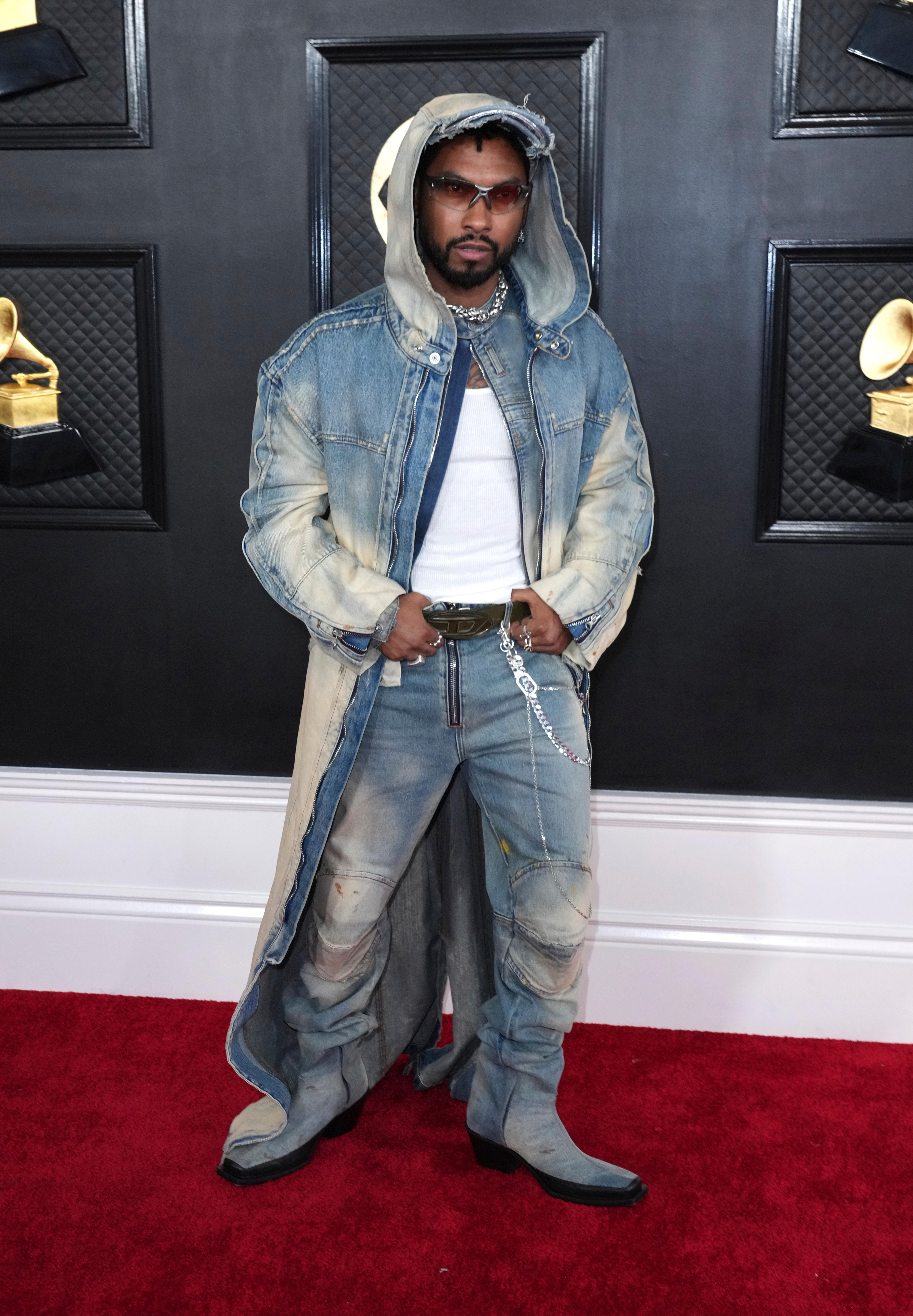Miguel wearing jeans, a white shirt and a hooded denim cloak. 