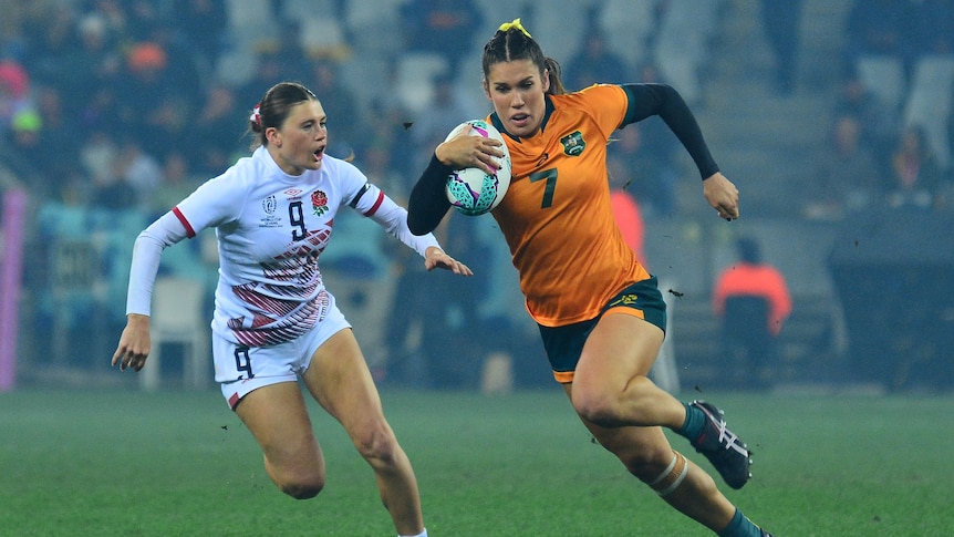 Australia's Charlotte Caslick runs with a ball away from England's Isla Norman-Bell of England during a rugby sevens game.