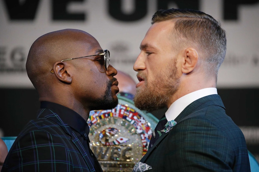 Floyd Mayweather Jr (L) and Conor McGregor stand face to face at a media conference.