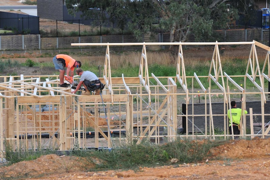 Men working to erect a house.