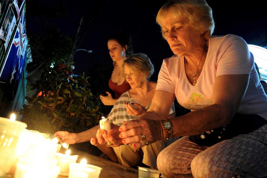 Tourists lights candle for Bali bombing victims.