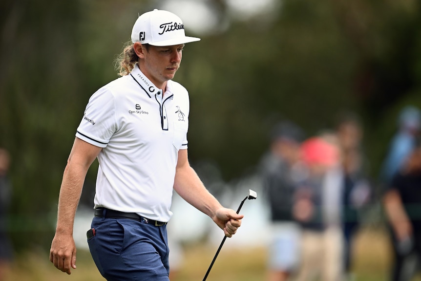 An Australian male golfer walks along the fairway at the Australian Open.