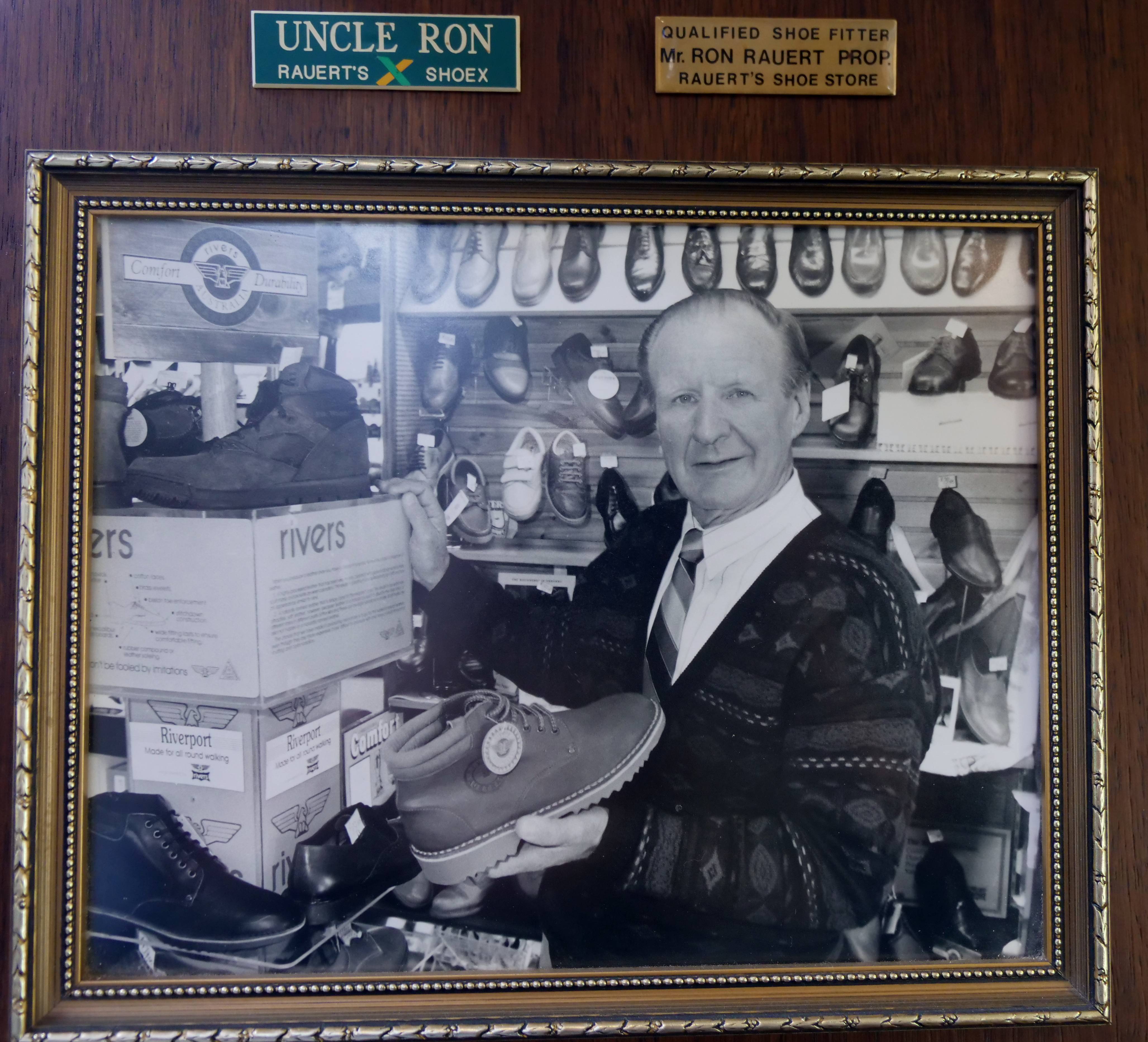 Una vieja foto de un hombre sosteniendo un zapato en una zapatería.