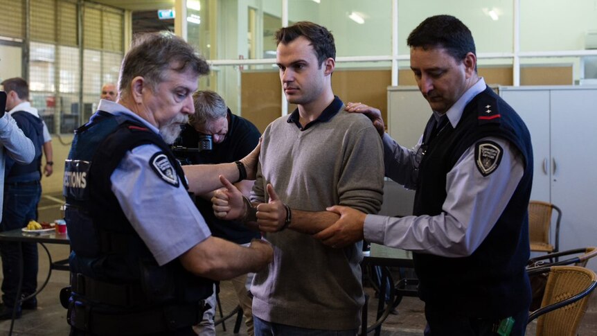 ABC Reporter Timothy Swanston in handcuffs at Borallan Correctional Centre