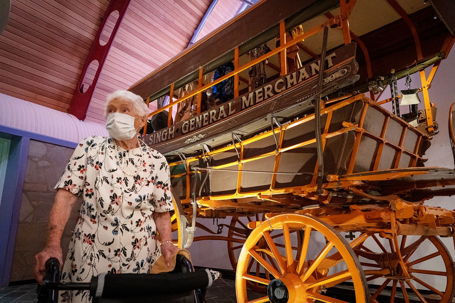 Amy Crosbie, stands with a face mask on, next to a wooden coach.