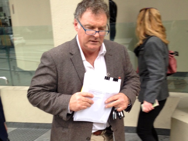 Road Culleton walking out of a Perth court holding papers.