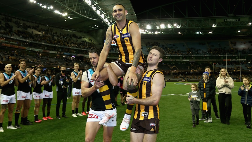 A Hawthorn AFL player is chaired from the field after playing his 400th match.