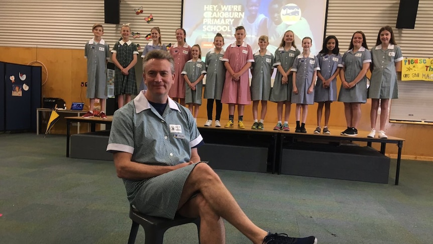 Students and a male principal wear dresses.