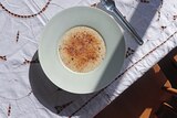 A bowl of rice pudding with a sprinkling of brown sugar on a sunny table, the recipe is made on the stove.