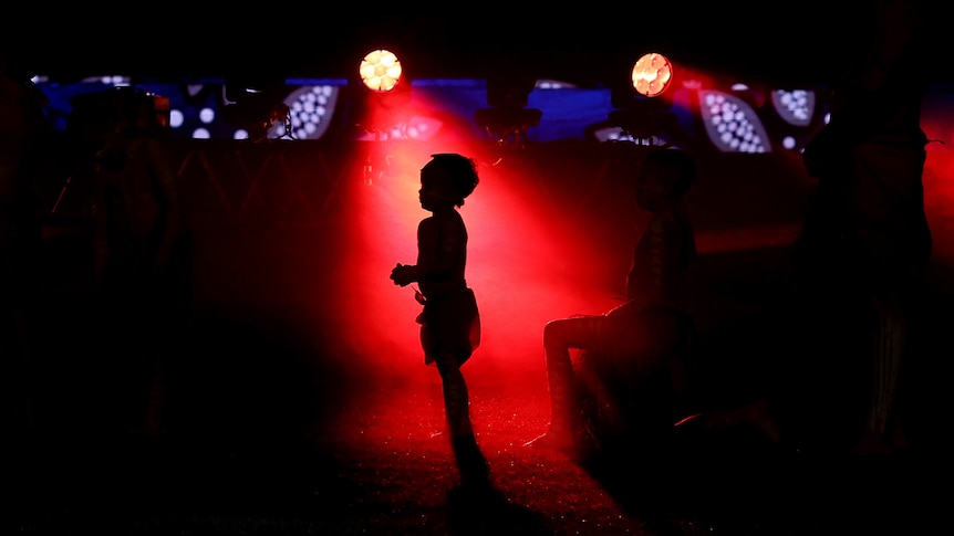 An Indigenous child silhouetted by red light before the Bulldogs-Dragons game.