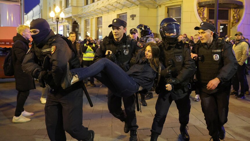 A woman is held by four police officers and carried away. 