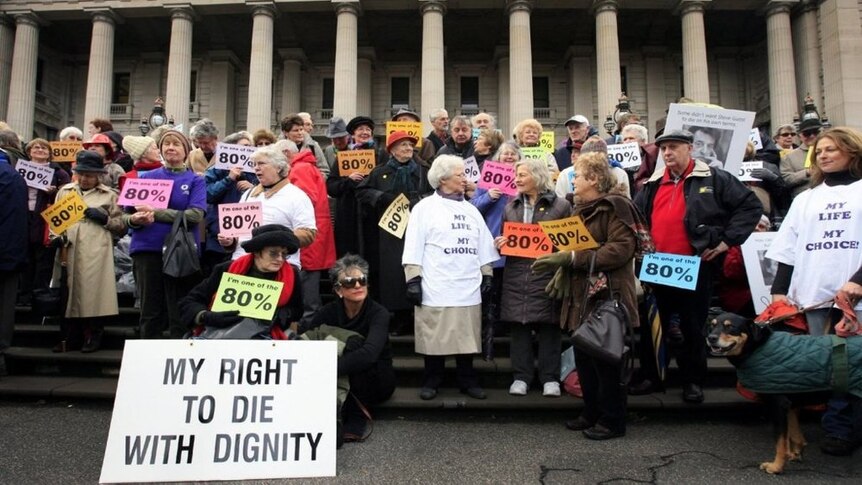 Protesters hold signs on the steps of Victorian Parliament as they lobby for assisted-dying to be legal.