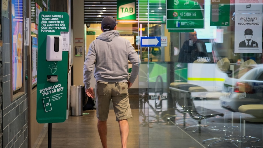 A man walks through the sliding glass door of the Melbourne TAB.