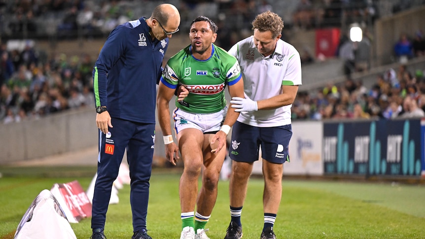 Jordan Rapana is helped by trainers after leaving a Canberra Raiders NRL game with a knee injury.
