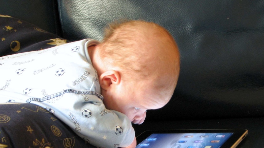 a baby with an iPad on a couch