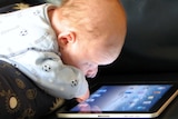 a baby with an iPad on a couch