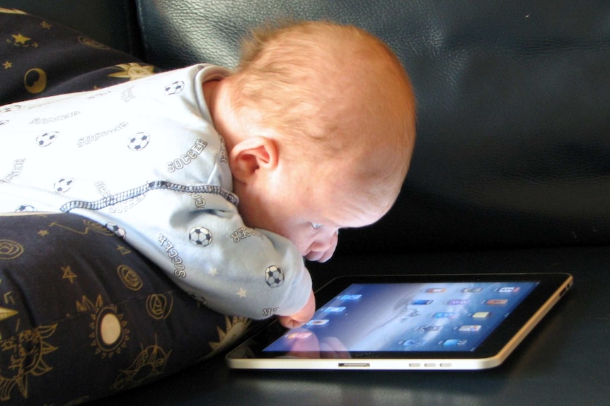 a baby with an iPad on a couch