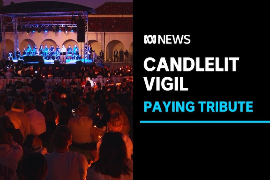 Candlelit Vigil, Paying Tribute: A crowd of people holding candles gather in front of a stage.