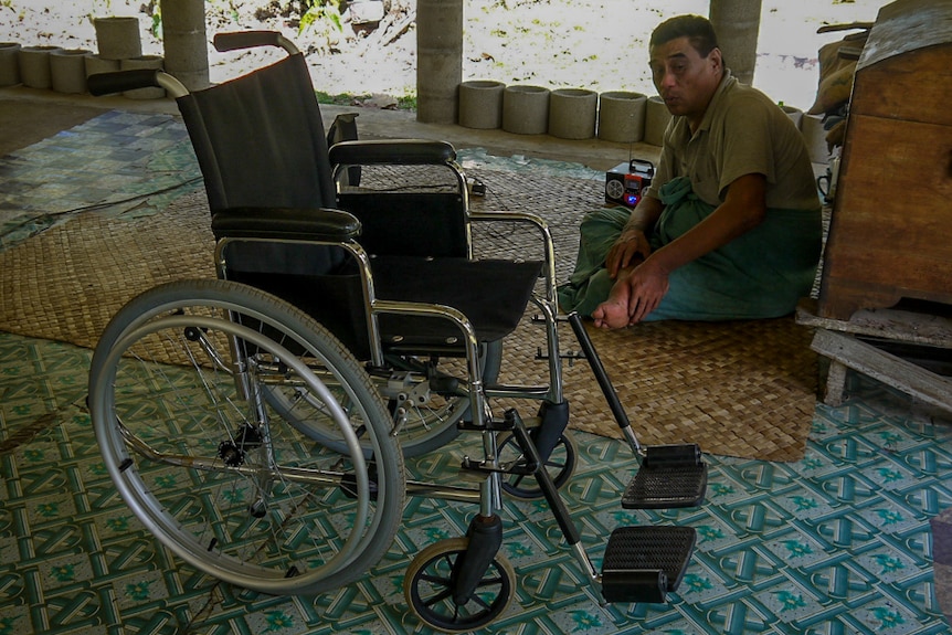 A client in Samoa sits next to an unsuitable wheelchair.