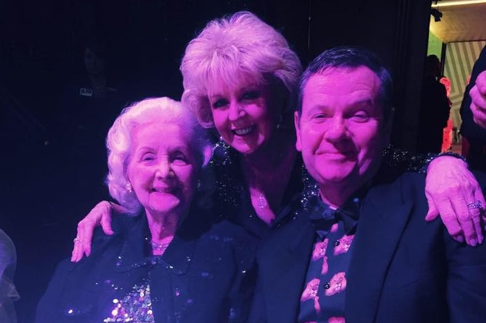 Val Jellay sits at a table with television personality Patti Newton and son Marty Fields in 2015.