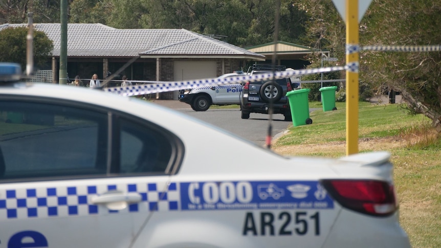 A police car and police tape is seen in front of a house