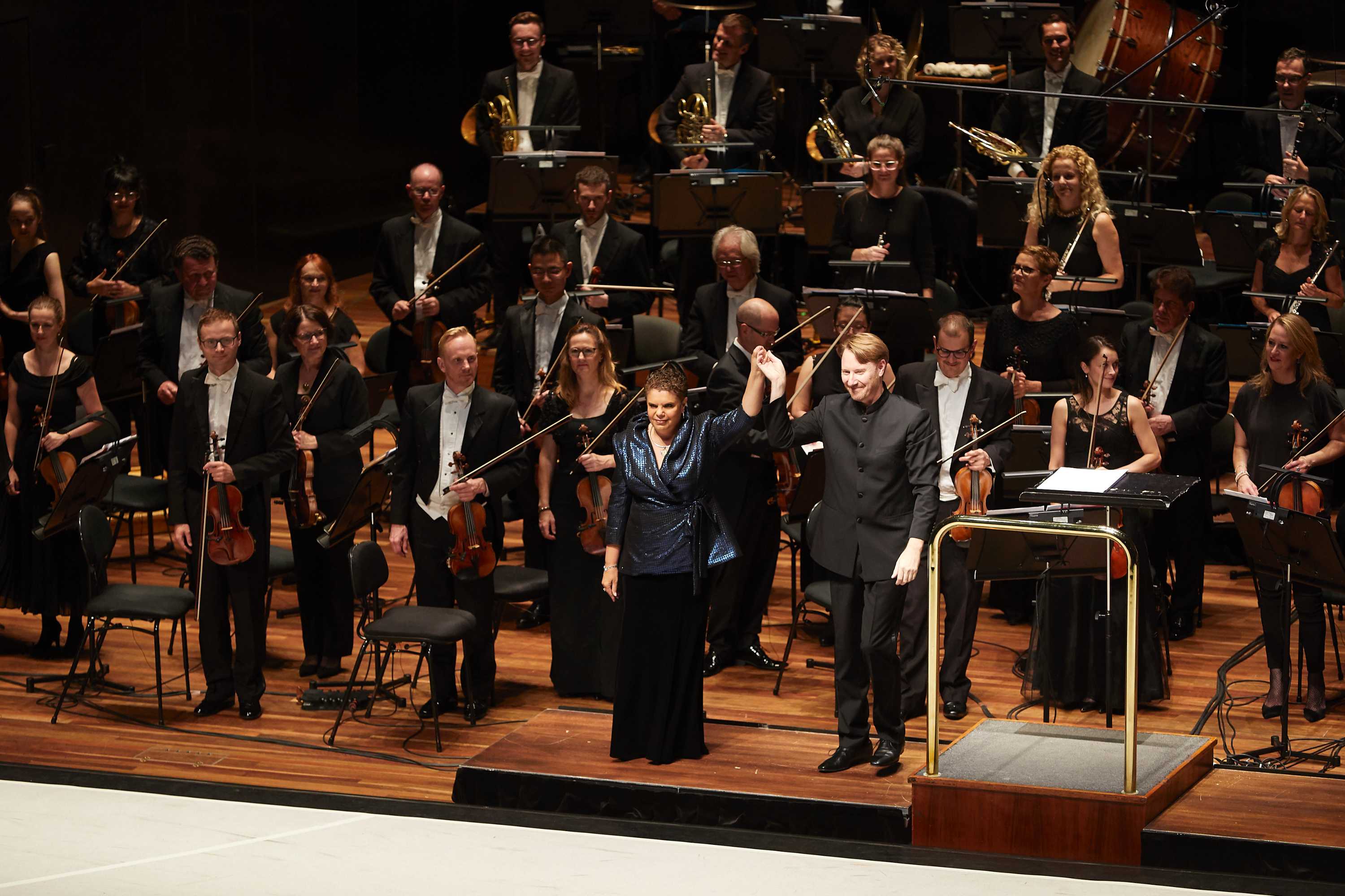 Soprano and composer Deborah Cheetham taking a bow with Benjamin Northey and the Melbourne Symphony Orchestra