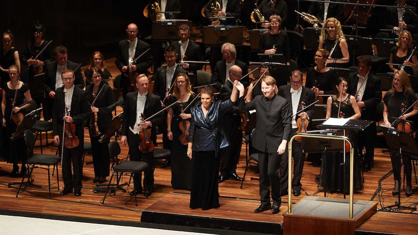 Soprano and composer Deborah Cheetham taking a bow with Benjamin Northey and the Melbourne Symphony Orchestra
