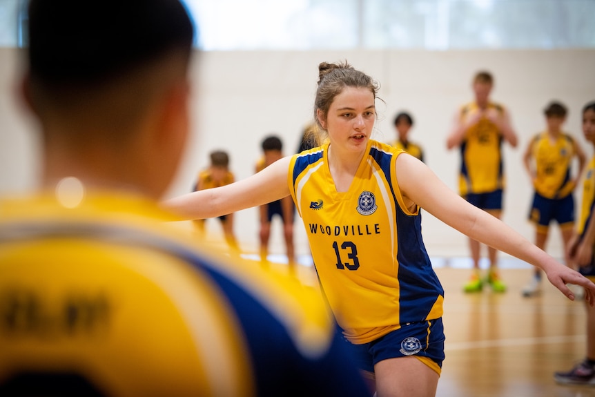 A girl in a yellow top playing basketball.