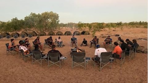 Men sitting around a camp fire in the outback.