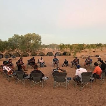 Men sitting around a camp fire in the outback.
