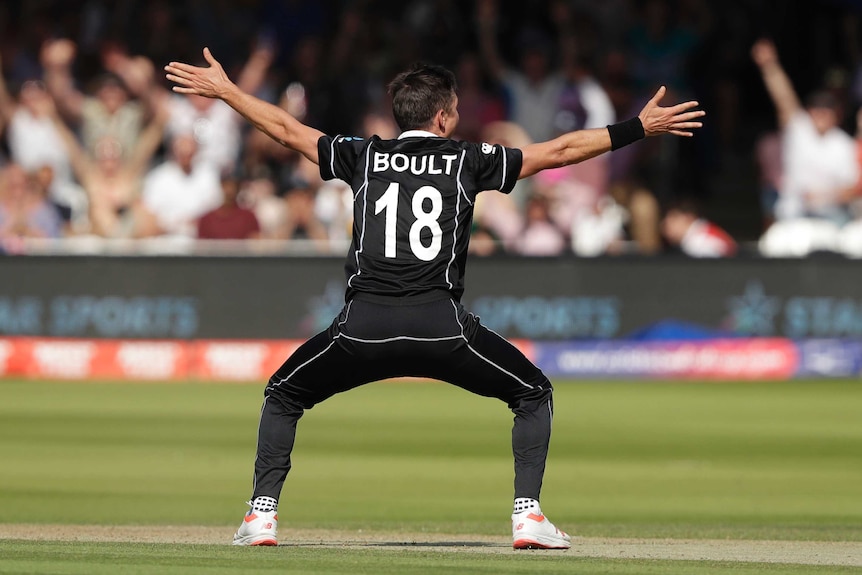 Trent Boult, with his back to camera, squats and holds his arms up outstretched.