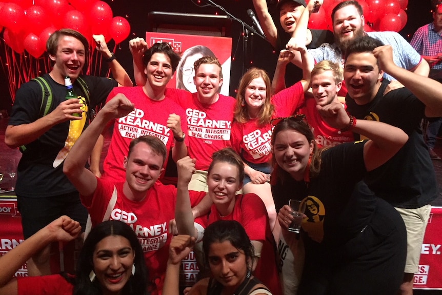 A dozen Labor supporters pose for photo, holding their fists in the air.