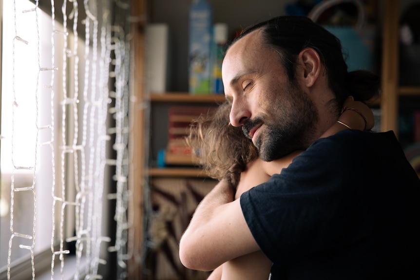 A man hugging a child with his eyes closed.