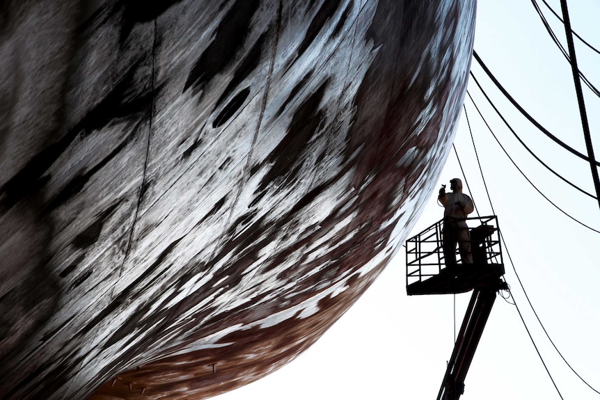 A person on a crane working on a ship in Croatia.