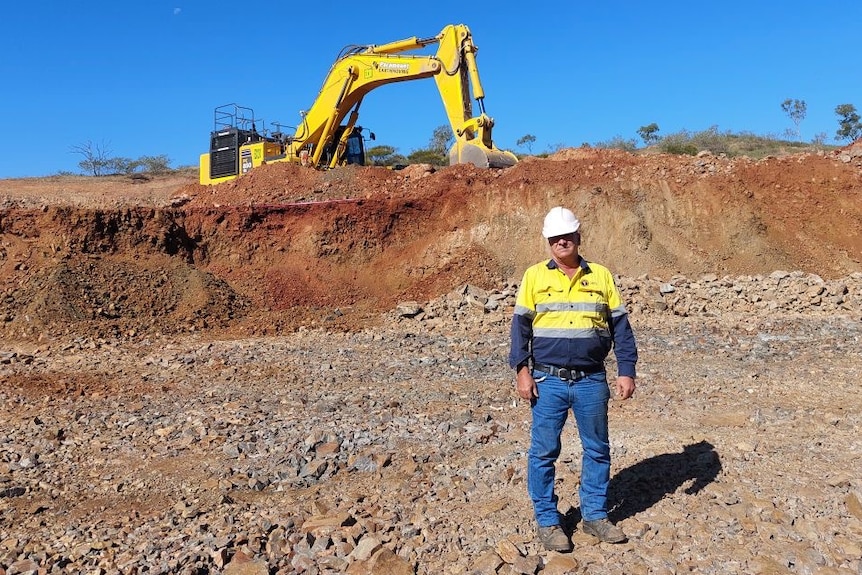 A man standing next to mining machinery.