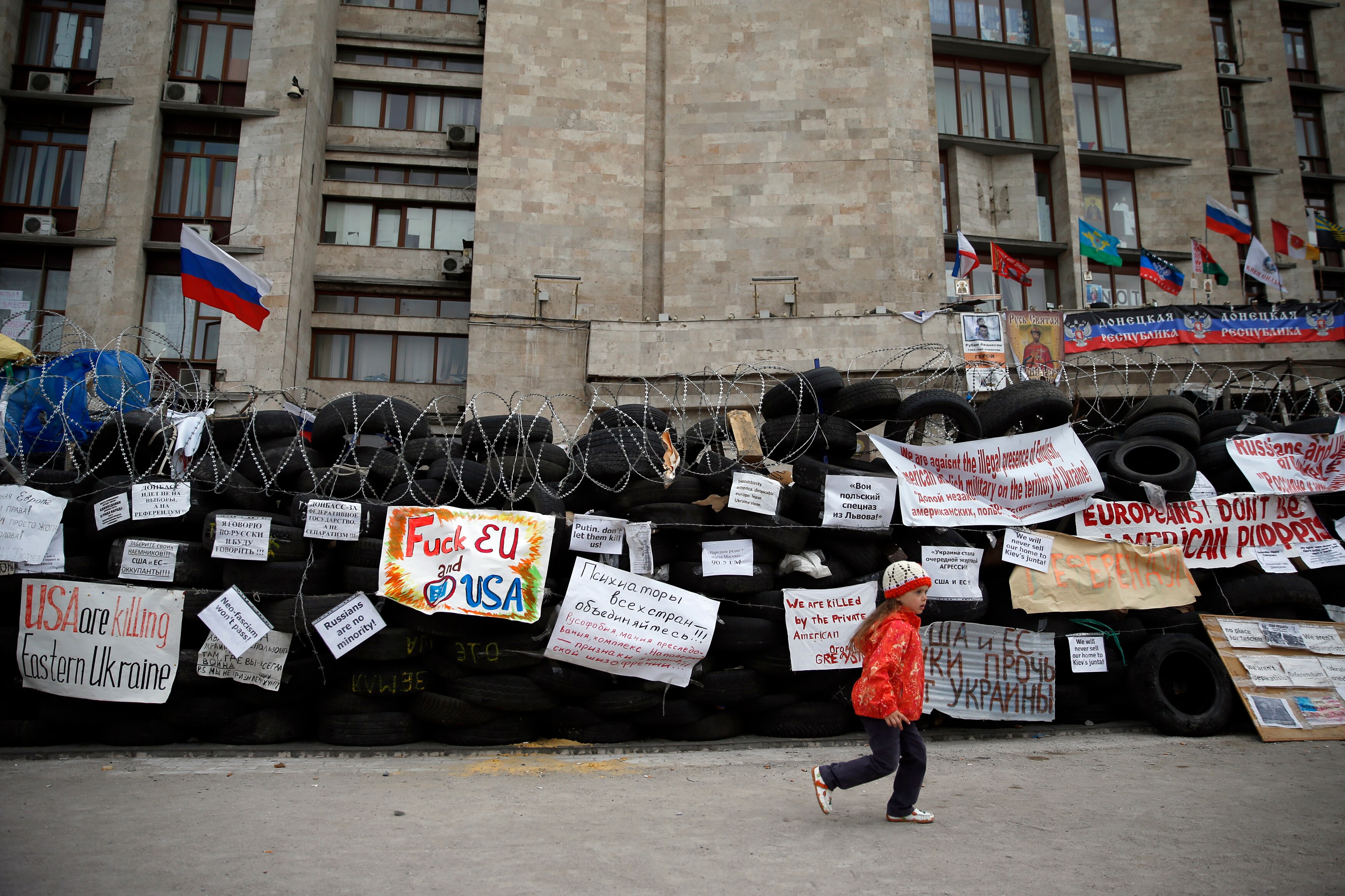 A girl runs near a barricade outside a regional government building in Donetsk.