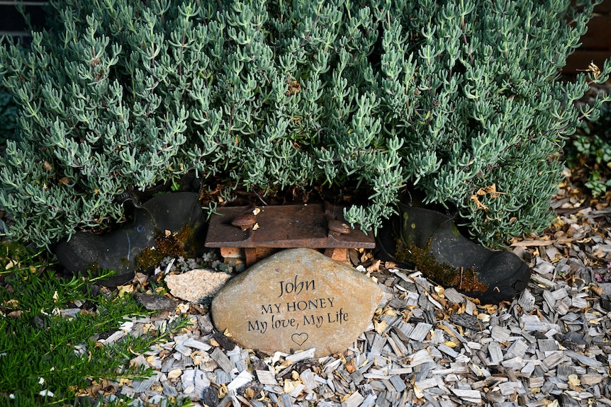 A plaque honoring John Kennedy in a garden next to a green shrub 