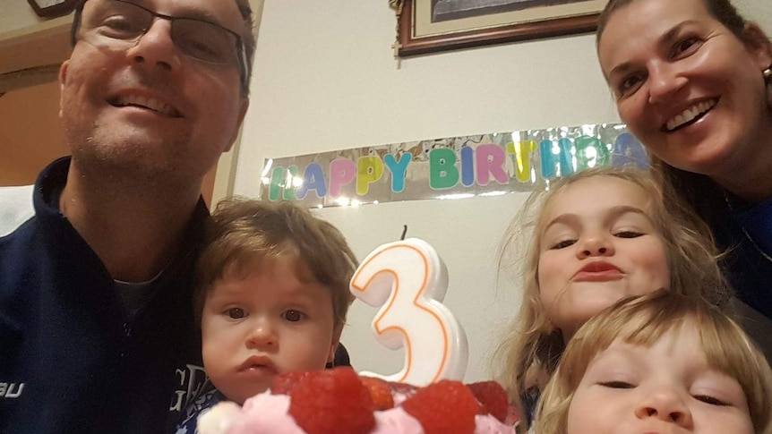 Tomislav and Katie Perinovic pose for a birthday photograph with their children, in front of a cake with a 'three' candle.