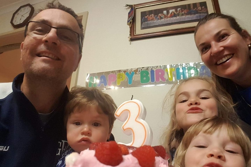 Tomislav and Katie Perinovic pose for a birthday photograph with their children, in front of a cake with a 'three' candle.