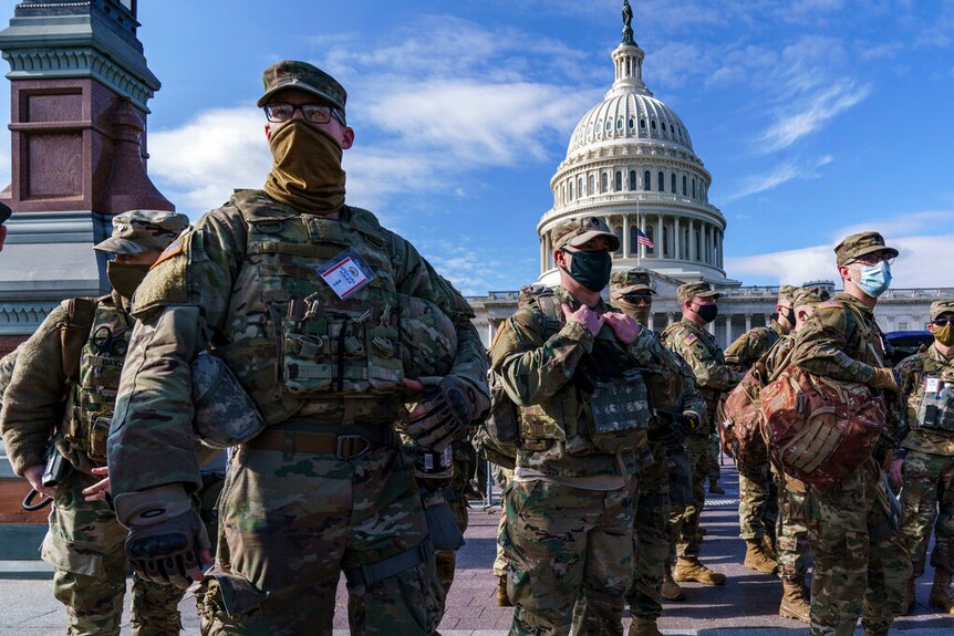 Troops stand in front of the US Capitol building.