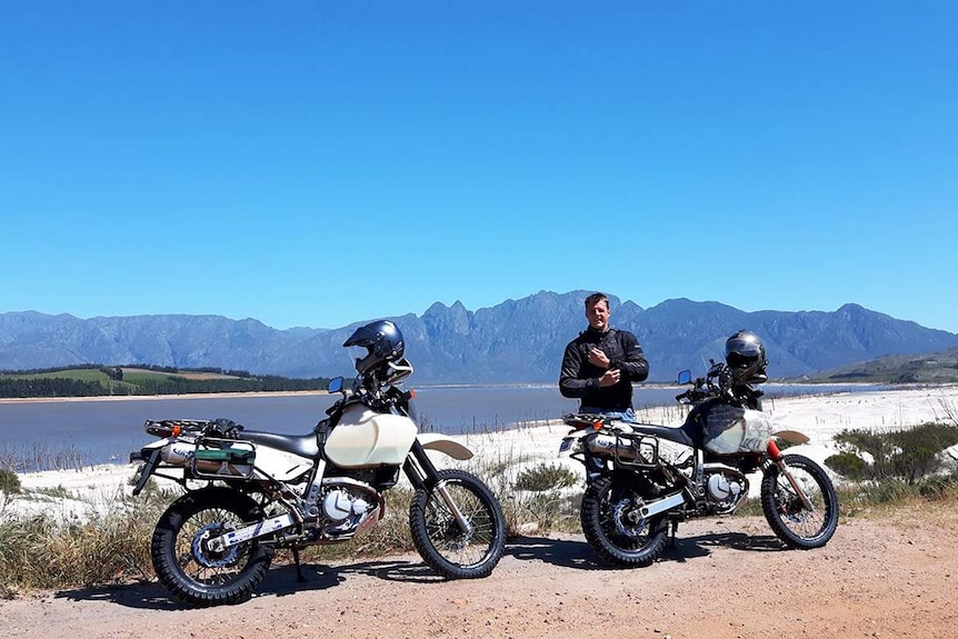 Dylan Reid stands beside his motorbike, with his brother's motorbike nearby, while travelling in South Africa in 2016.