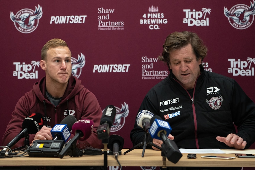 Two men seated at a desk behind microphones