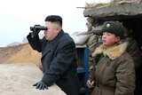 Kim Jong-un looks out with binoculars.