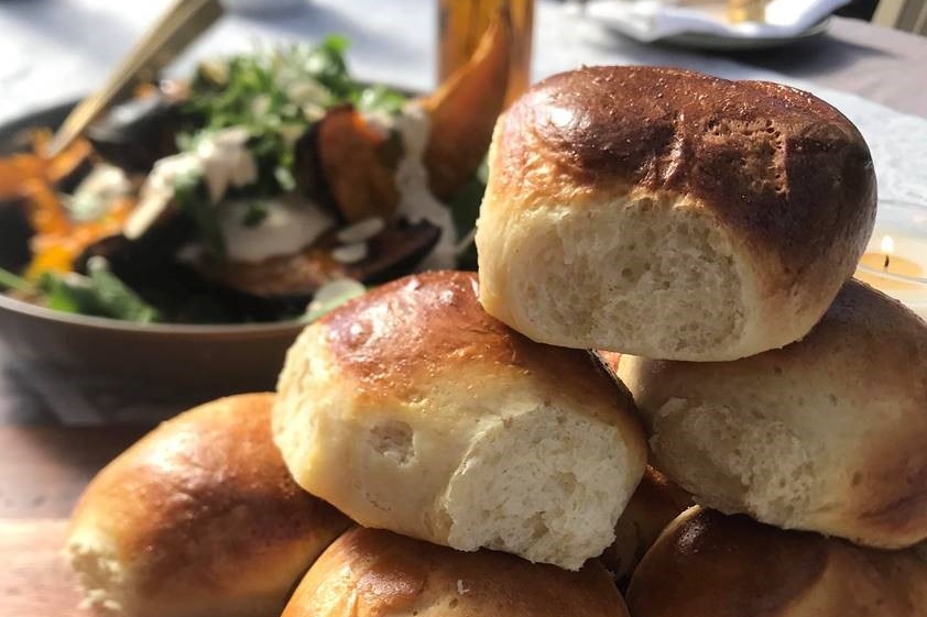 a golden stack of perfect milk buns on a nicely set table