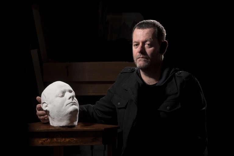 Clayton Tremlett sitting down with his own personal death mask made of solid plaster.