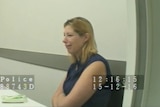 A woman with blonde hair cries while sitting in a police interview room